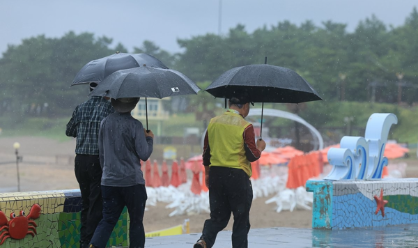 비가 쏟아진 30일 오전 제주시 이호해수욕장에서 우산을 든 이들이 산책하고 있다. [사진=연합뉴스]